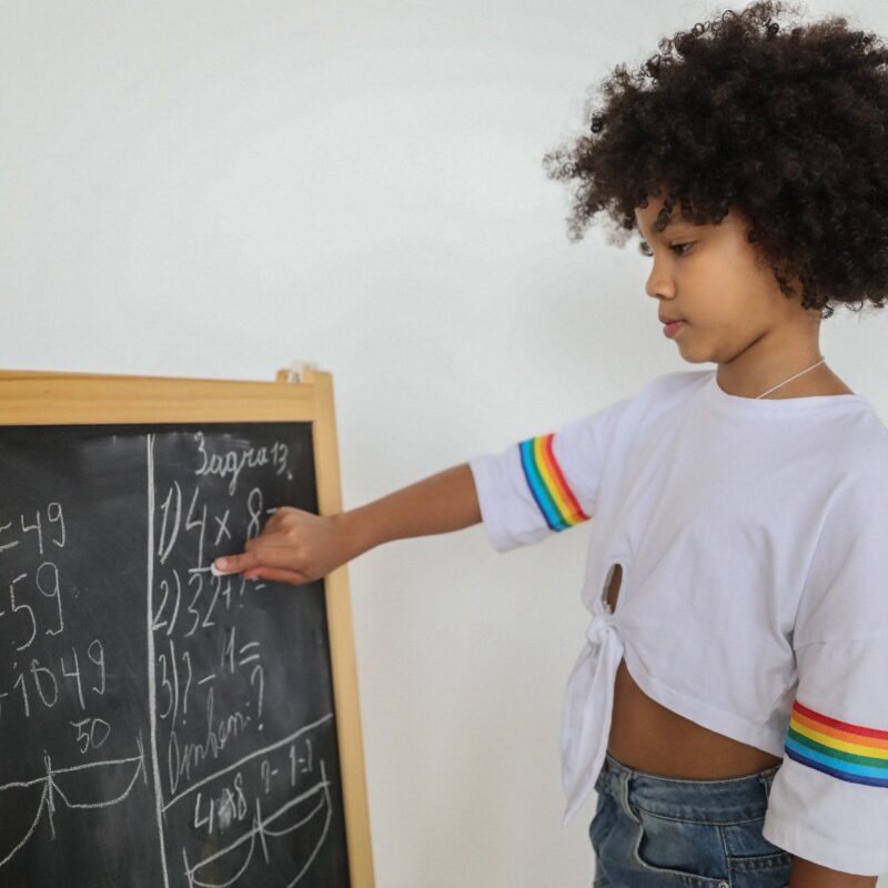 enfant montrant un tableau avec des calculs mathématiques